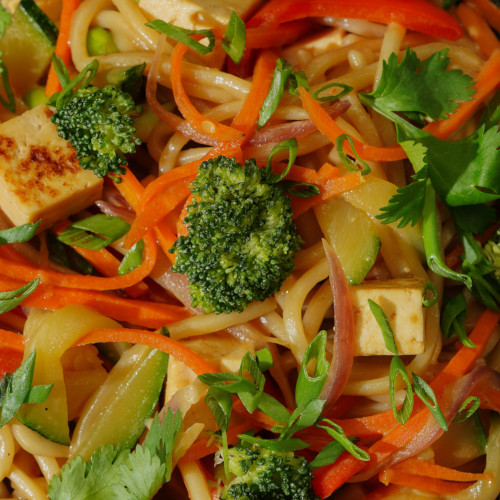 Sauté de légumes colorés avec nouilles de riz, tofu, brocoli, poivrons et coriandre fraîche en gros plan